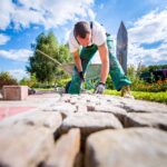 Handwerker verlegt Pflastersteine in einer Gartenanlage