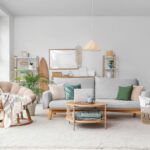 Ein geräumiges Wohnzimmer mit einem hellen Holz-Couchtisch, einem großen grauen Sofa und grünen Kissen, ergänzt durch natürliche Dekoelemente.